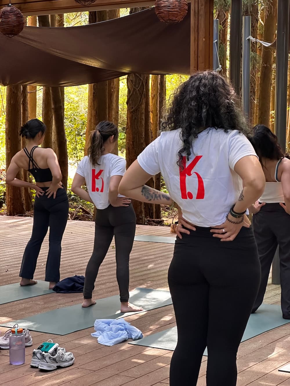 K-Pole Retreat participants doing morning yoga outdoors in a pergola in the woods on Jeju Island.